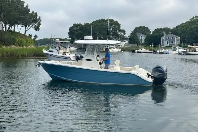 Slide: The Image of 2023 Cobia 240 Center Console boat on calm water near shoreline homes. - 4