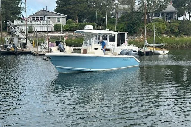 Slide: The Image of 2023 Cobia 240 Center Console boat docked in a serene marina setting. - 6