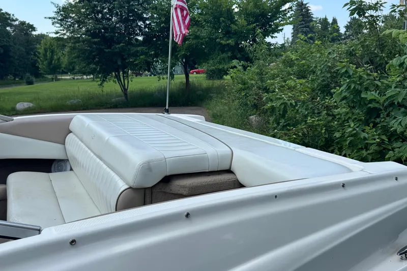Slide: The Image of 2004 Regal 1800 LSR boat interior with white seating and American flag, surrounded by greenery. - 4