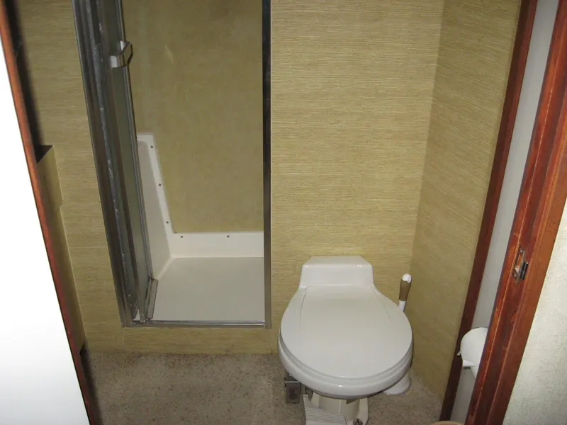 Slide: The Image of 1978 Bertram 42 Convertible bathroom with shower and toilet, featuring beige walls. - 25