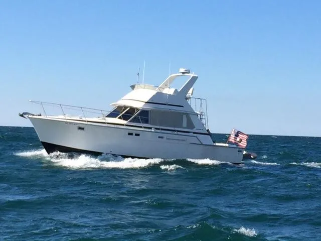 Slide: The Image of 1978 Bertram 42 Convertible yacht cruising on open sea with American flag. - 5