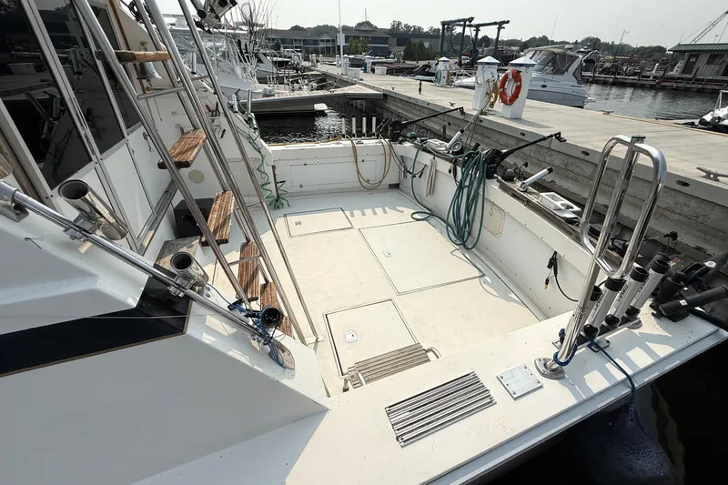 Slide: The Image of 1978 Bertram 42 Convertible boat docked, featuring spacious deck and fishing equipment. - 8