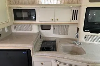 Slide: The Image of Sea Ray 340 Sundancer kitchen with microwave, stove, sink, and compact fridge. - 3