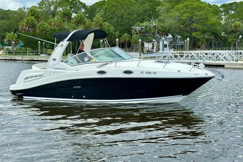 The Image of 2006 Sea Ray 260 Sundancer boat cruising on a calm river near a marina. - 0