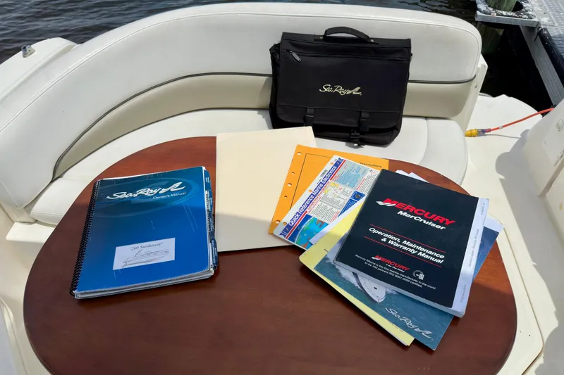 Slide: The Image of 2006 Sea Ray 260 Sundancer manuals and documents on boat seating area. - 22