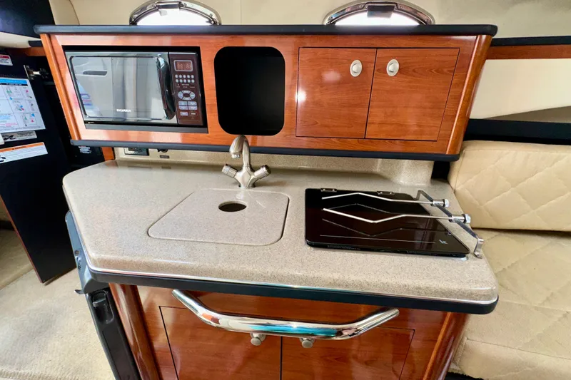 Slide: The Image of 2006 Sea Ray 260 Sundancer interior kitchen with microwave, sink, and stove. - 32