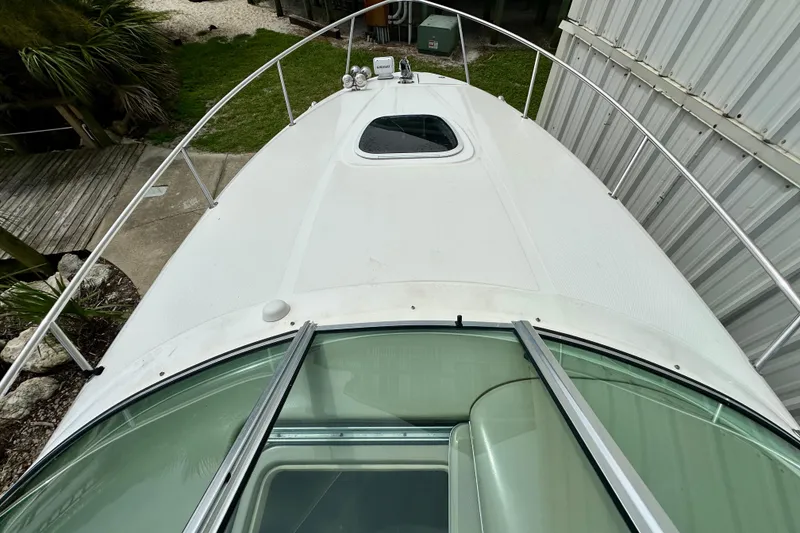 Slide: The Image of 2006 Sea Ray 260 Sundancer boat deck with railing and hatch, docked near greenery. - 8