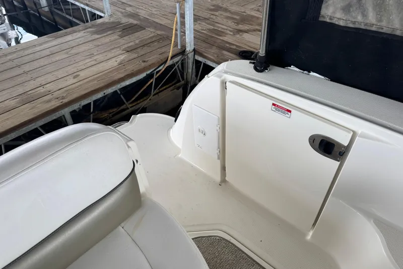 Slide: The Image of 2007 Sea Ray 260 Sundancer boat interior near dock, featuring seating and storage compartment. - 16