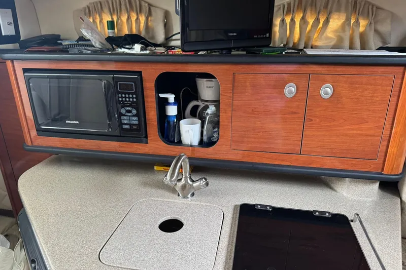 Slide: The Image of 2007 Sea Ray 260 Sundancer interior with microwave, sink, and wooden cabinetry. - 29