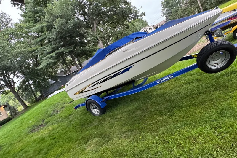 Slide: The Image of 2008 Glastron MX175 boat on trailer, parked on grass with trees in background. - 13