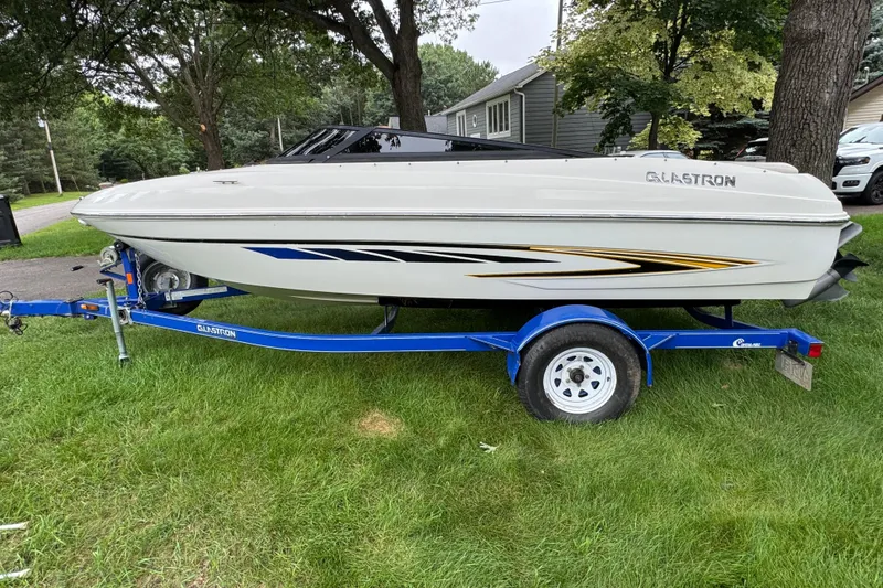 Slide: The Image of 2008 Glastron MX175 boat on blue trailer, parked on grass. - 2