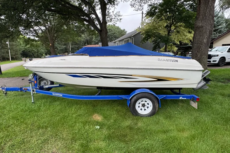 Slide: The Image of 2008 Glastron MX175 boat on trailer with cover, parked on grass. - 4