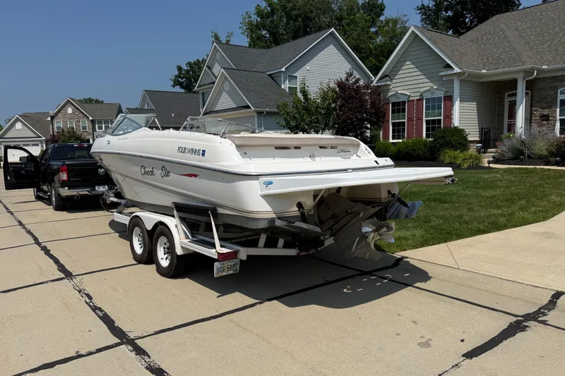 Slide: The Image of Four Winns boat on trailer in suburban driveway, sunny day, residential neighborhood. - 2