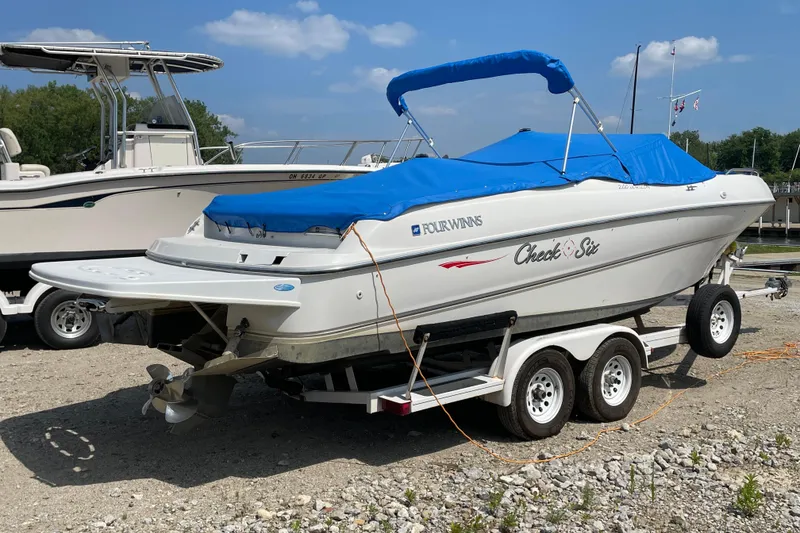 Slide: The Image of Four Winns boat with blue cover on trailer, parked outdoors. - 7