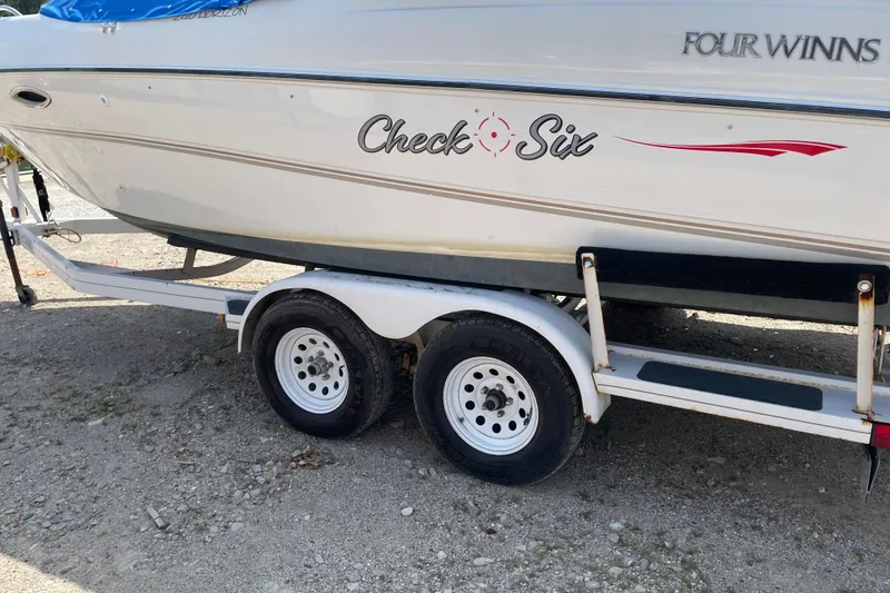 Slide: The Image of Four Winns boat on trailer with "Check Six" decal, parked on gravel. - 8