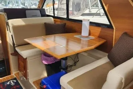 Slide: The Image of 2013 Cutwater C-26 interior with wooden table, cushioned seating, and window view. - 9