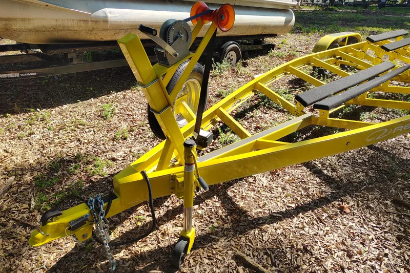 Slide: The Image of Yellow boat trailer for 2006 Regal 2250 Cuddy, parked on leaf-covered ground. - 23