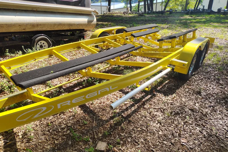 Slide: The Image of Yellow Regal 2250 Cuddy 2006 boat trailer parked on leafy ground. - 24