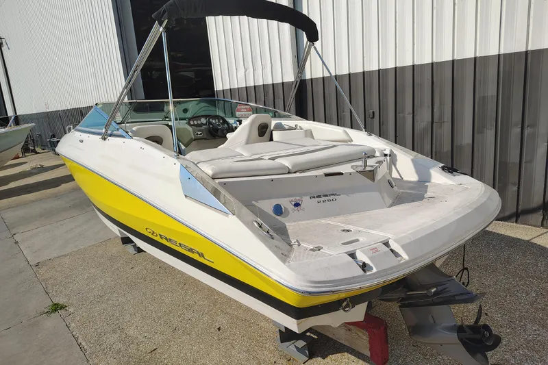 Slide: The Image of 2006 Regal 2250 Cuddy boat with yellow accents, parked outdoors near a building. - 3