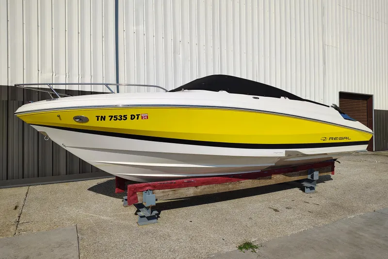 Slide: The Image of 2006 Regal 2250 Cuddy boat with yellow and white exterior, displayed on a stand. - 4