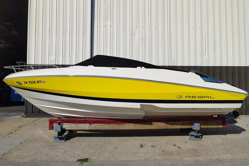 Slide: The Image of 2006 Regal 2250 Cuddy boat with yellow and white exterior, displayed on a stand. - 7