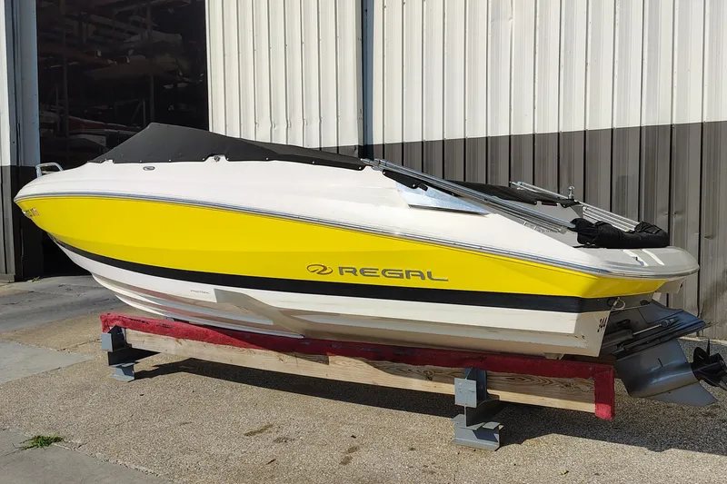 Slide: The Image of 2006 Regal 2250 Cuddy boat with yellow and white exterior, parked on a stand. - 8