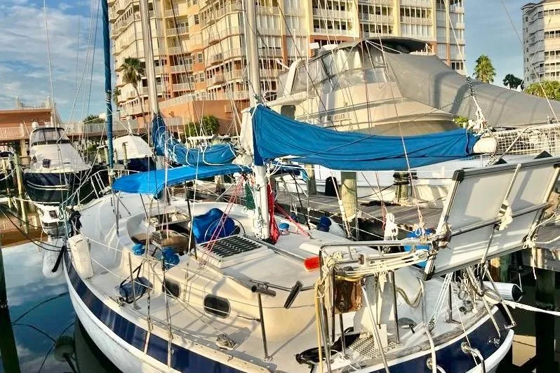 Slide: The Image of 1978 Morgan 415 sailboat docked at marina with blue sails and nearby buildings. - 0