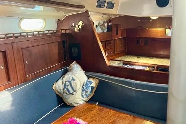 Slide: The Image of Interior of a 1978 Morgan 415 sailboat with wooden cabinetry and blue seating. - 18