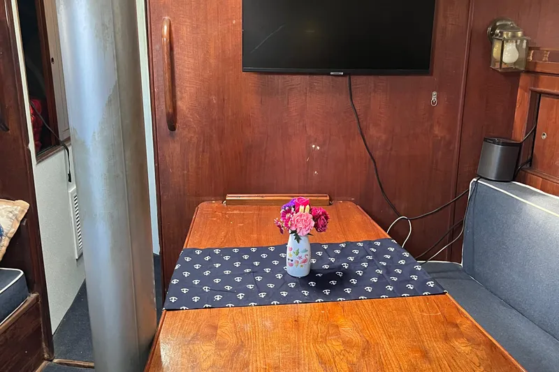 Slide: The Image of Cozy 1978 Morgan 415 yacht interior with wooden table, floral centerpiece, and wall-mounted TV. - 19