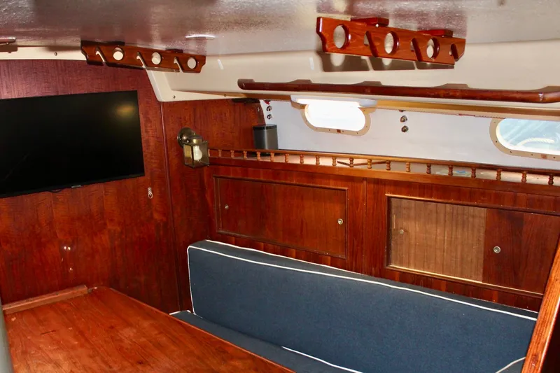 Slide: The Image of Interior of a 1978 Morgan 415 sailboat with wooden cabinetry and blue seating. - 20