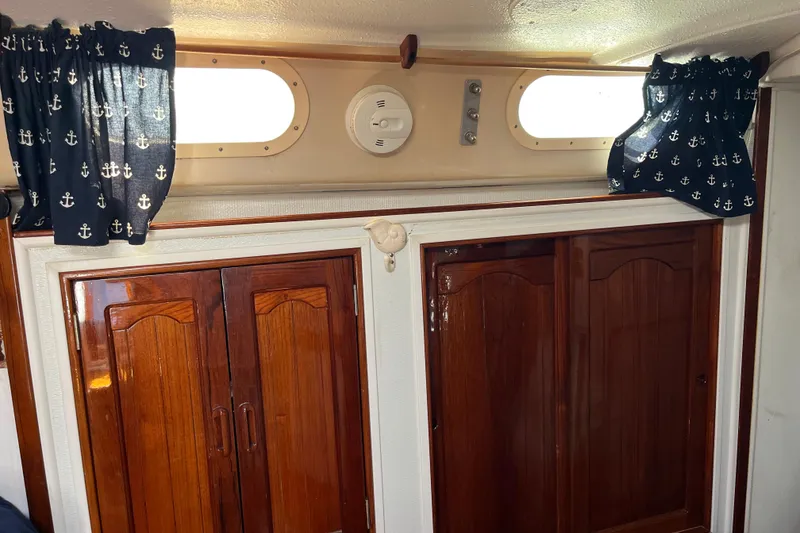 Slide: The Image of Interior of a 1978 Morgan 415 sailboat with wooden cabinets and nautical curtains. - 24