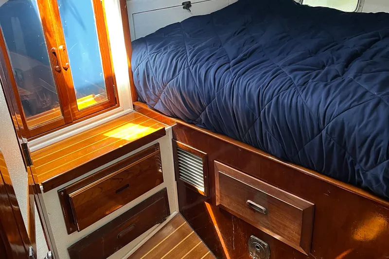 Slide: The Image of Cozy cabin interior of 1978 Morgan 415 sailboat with wooden drawers and blue bedding. - 27