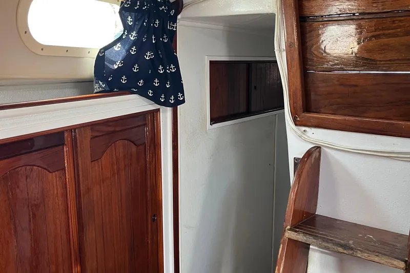 Slide: The Image of Interior of a 1978 Morgan 415 sailboat with wooden finishes and nautical-themed curtain. - 28
