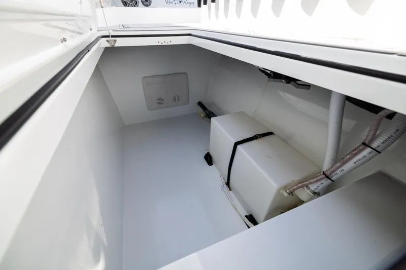 Slide: The Image of Storage compartment of 2023 Freeman 47 boat, featuring a secured white tank and piping. - 113