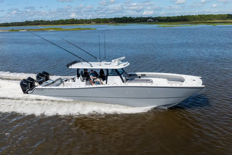 Slide: The Image of 2023 Freeman 47 boat cruising on a calm lake with multiple outboard engines. - 24