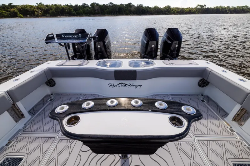 Slide: The Image of 2023 Freeman 47 boat interior with fishing setup and dual engines on a calm lake. - 40