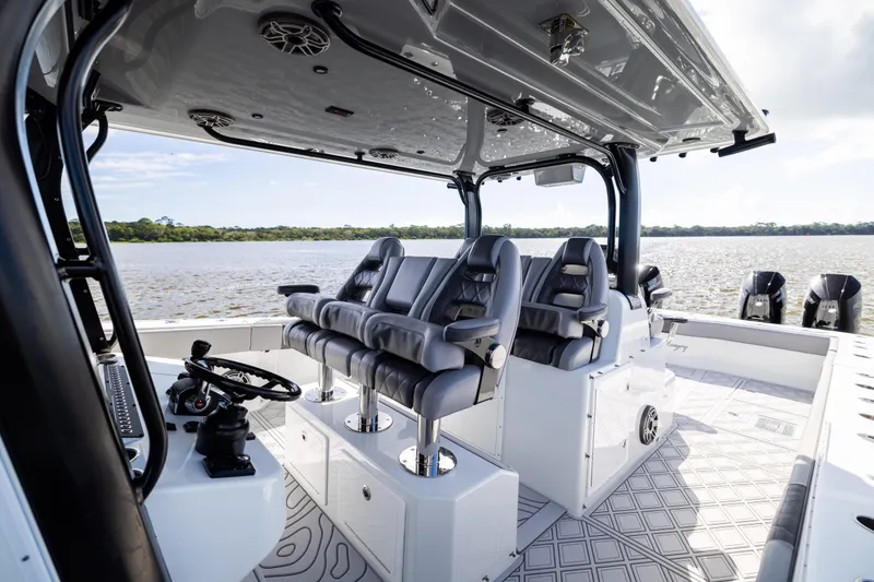 Slide: The Image of 2023 Freeman 47 boat interior with luxury seating and steering wheel, overlooking serene water. - 61