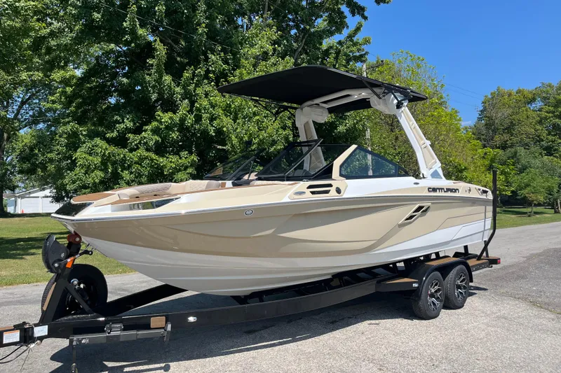 Slide: The Image of 2025 Centurion Ri230 boat on trailer, parked outdoors with trees in background. - 7