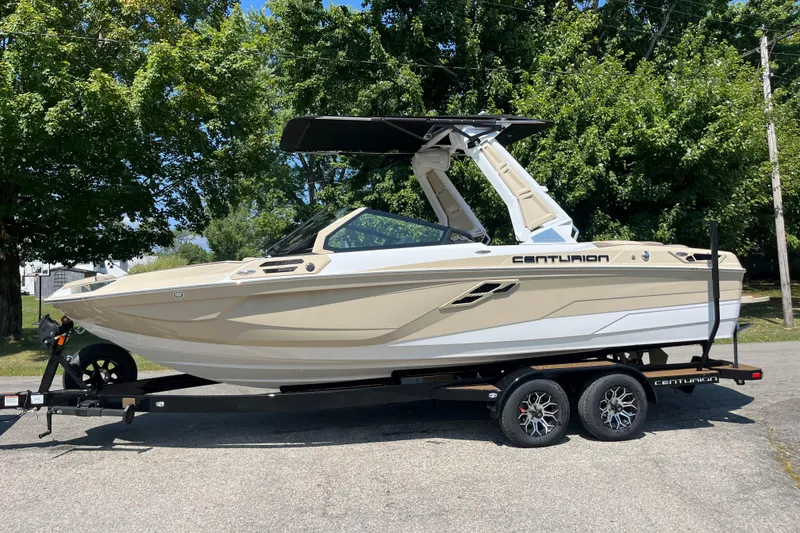 Slide: The Image of 2025 Centurion Ri230 boat on trailer, parked outdoors with trees in background. - 8
