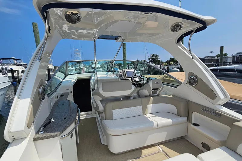 Slide: The Image of 2015 Chaparral 310 Signature boat interior with helm, seating, and modern amenities at a marina. - 12