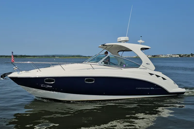 Slide: The Image of 2015 Chaparral 310 Signature boat cruising on calm waters under clear blue sky. - 2