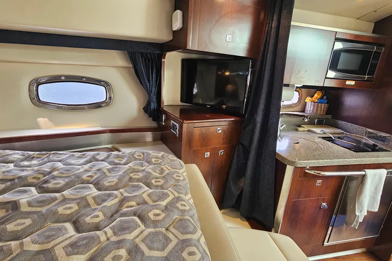 Slide: The Image of 2015 Chaparral 310 Signature cabin with bed, kitchenette, and TV. - 28