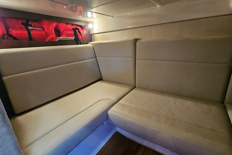 Slide: The Image of 2015 Chaparral 310 Signature cabin interior with beige seating and life jackets. - 32