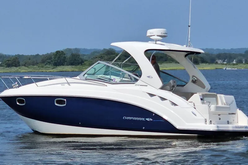 Slide: The Image of 2015 Chaparral 310 Signature boat cruising on a calm lake with scenic background. - 6