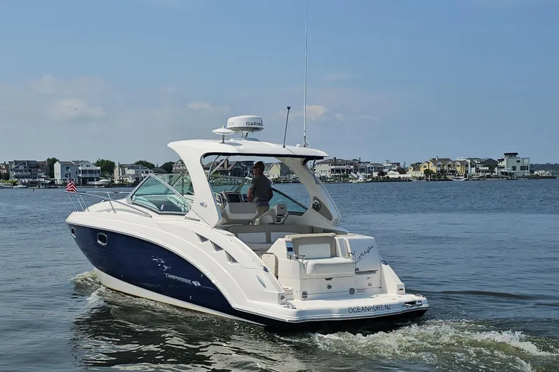 Slide: The Image of 2015 Chaparral 310 Signature boat cruising near coastal homes on a sunny day. - 9