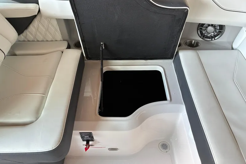 Slide: The Image of 2025 Regal LS2 boat interior storage compartment with open lid, featuring cushioned seating. - 36