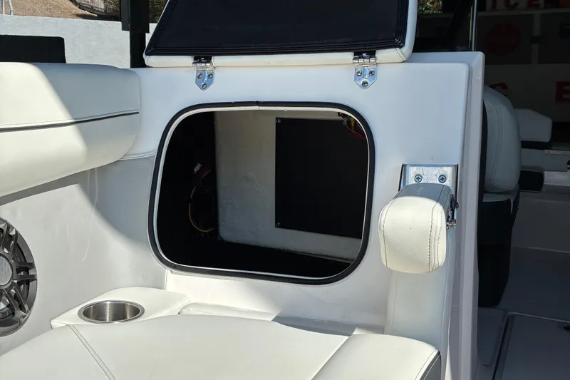 Slide: The Image of 2025 Regal LS2 boat interior storage compartment with white seating and cup holder. - 43