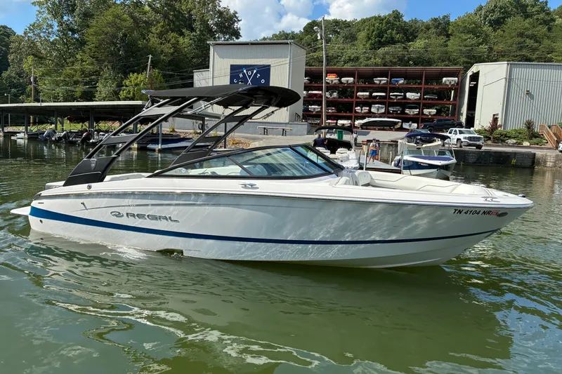 Slide: The Image of 2025 Regal LS2 boat docked on a calm lake with marina background. - 7