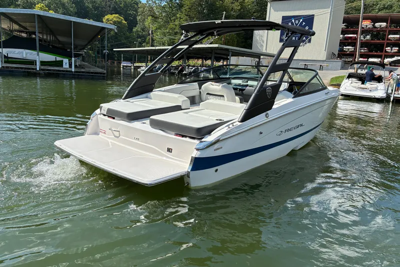Slide: The Image of 2025 Regal LS2 boat on water near marina, showcasing sleek design and spacious seating. - 9