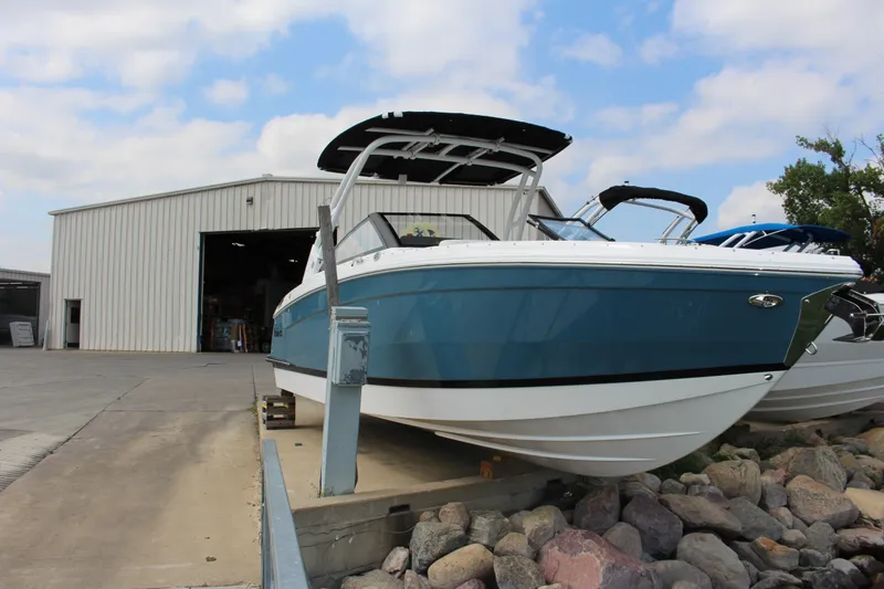 Slide: The Image of 2025 Cobalt R8 boat in front of a warehouse, displayed on a rocky platform. - 2
